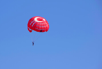 Red parachute flying in the blue sky.