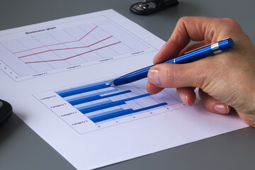hand with a pen on the background of a business graph