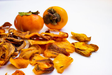Chocolate persimmon, kinglet. Dried thin slices, fruit chips. Healthy food and snacks. Fruits are orange and brown in color. Light background.