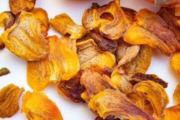 Chocolate persimmon, kinglet. Dried thin slices, fruit chips. Healthy food and snacks. Fruits are orange and brown in color. Light background.