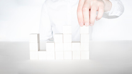 Closeup of businessman making a pyramid with empty wooden cubes. Concept of business hierarchy and human resources.