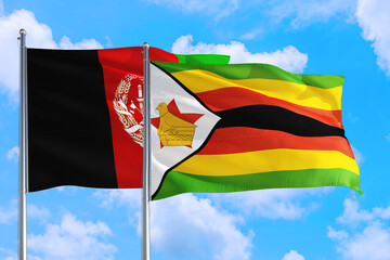 Zimbabwe and Afghanistan national flag waving in the wind on a deep blue sky together. High quality fabric. International relations concept.