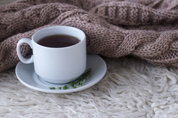 a Cup of tea on a white wool rug on a background of a knitted blanket