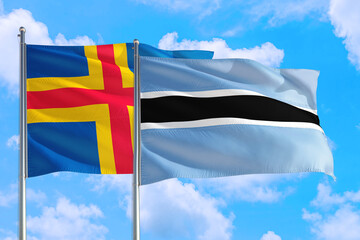 Botswana and Aland Islands national flag waving in the windy deep blue sky. Diplomacy and...