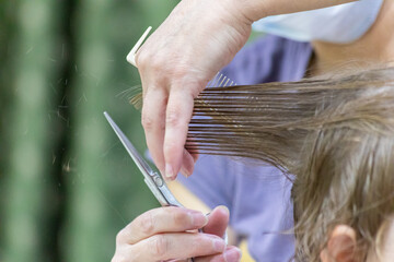 First haircut for a young girl in a hairstyle studio. Cutting split ends with scissors.