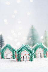 Three Christmas gingerbread houses on white snow. Selective focus.