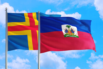 Haiti and Aland Islands national flag waving in the windy deep blue sky. Diplomacy and international relations concept.