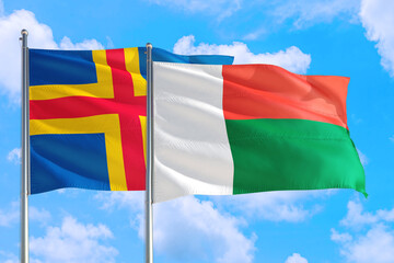 Madagascar and Aland Islands national flag waving in the windy deep blue sky. Diplomacy and international relations concept.