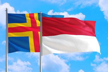 Monaco and Aland Islands national flag waving in the windy deep blue sky. Diplomacy and international relations concept.