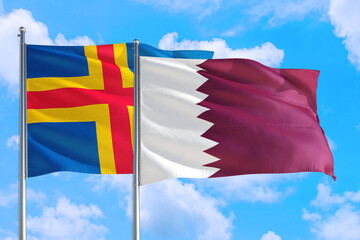 Qatar and Aland Islands national flag waving in the windy deep blue sky. Diplomacy and...