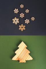 The zero waste new year concept as a handmade wooden fir tree and falling wooden snowflakes on the grey and green background.