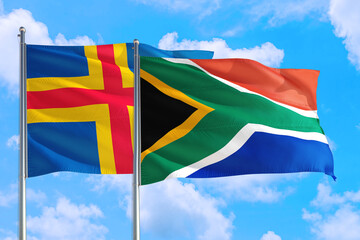 South Africa and Aland Islands national flag waving in the windy deep blue sky. Diplomacy and international relations concept.