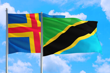 Tanzania and Aland Islands national flag waving in the windy deep blue sky. Diplomacy and international relations concept.