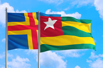 Togo and Aland Islands national flag waving in the windy deep blue sky. Diplomacy and international relations concept.