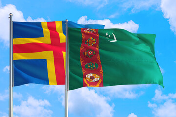 Turkmenistan and Aland Islands national flag waving in the windy deep blue sky. Diplomacy and...