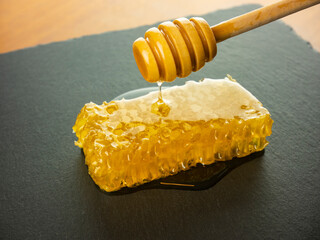 honeycomb with honey dipper on black slate plate