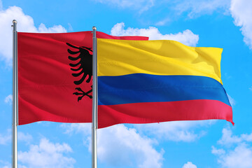Colombia and Albania national flag waving in the windy deep blue sky. Diplomacy and international relations concept.