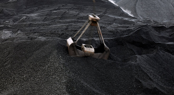 Coal loading excavator, heaps of coal. Excavator movement effect