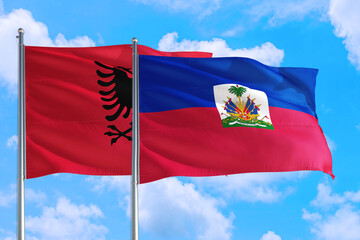 Haiti and Albania national flag waving in the windy deep blue sky. Diplomacy and international relations concept.