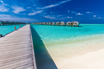 Jetty over atoll and a tropical resort island in Maldives