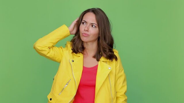 Preoccupied young woman 20s in yellow leather jacket isolated on green background in studio. People lifestyle concept. Put hand on head holding index finger up with great new idea showing thumbs up