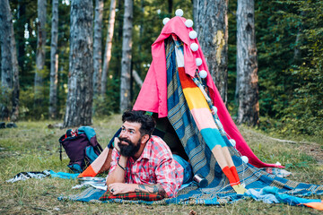 Handsome bearded man inside camping tent. You cant buy love. Happy man in summer. Hiking and outdoor recreation concept with flat camping travel. Camping outdoor back to nature.