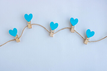 Small clothespins and blue hearts on a string on a white background