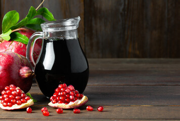 Pomegranate molasses in glass bowl, pomegranate sour sauce with fresh ripe whole and split...