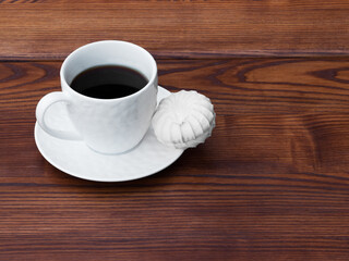 Obraz premium White cup of coffee and pink zefir on the wooden background. Traditional russian sweets like marshmallow. Copy space.