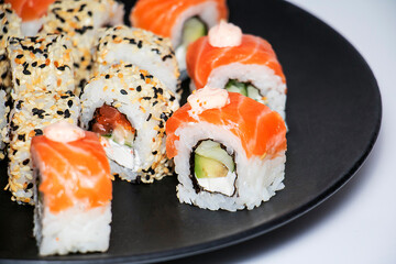 
Different kind of rolls and sushi on black plate isolated over white background