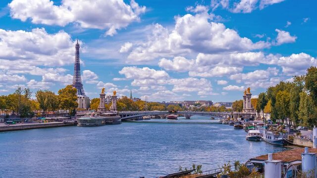 A timelapse of the Eiffel Tower along the river Seine with flyboats passing by with motion blur.Sunny but cloudy autumn day with golden yellow leaves,paris city riverside bay view bridge panorama