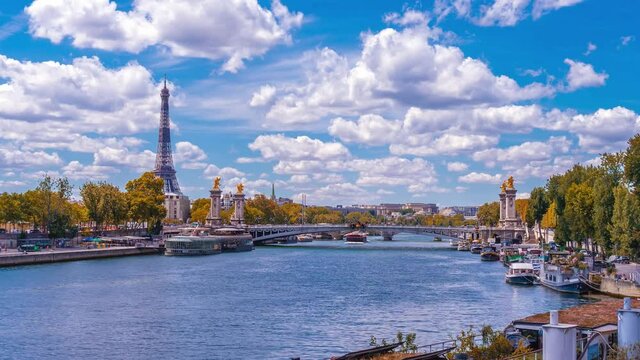 A timelapse of the Eiffel Tower along the river Seine with flyboats passing by with motion blur.Sunny but cloudy autumn day with golden yellow leaves,paris city riverside bay view bridge panorama