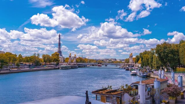 A timelapse of the Eiffel Tower along the river Seine with flyboats passing by with motion blur.Sunny but cloudy autumn day with golden yellow leaves,paris city riverside bay view bridge panorama
