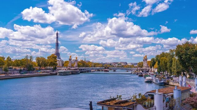 A timelapse of the Eiffel Tower along the river Seine with flyboats passing by with motion blur.Sunny but cloudy autumn day with golden yellow leaves,paris city riverside bay view bridge panorama