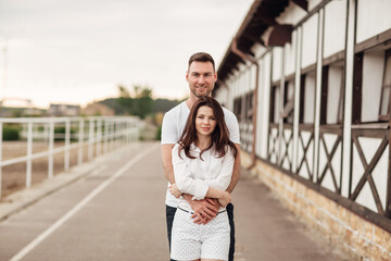 happy young man and woman having fun outdoors on a warm summer day. couple is hugging near horse rancho