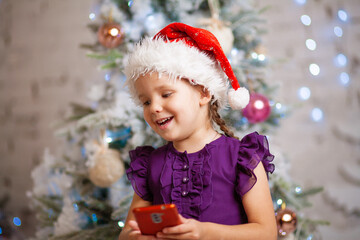 New Year's portrait of a little cute girl against the background of the Christmas tree, the child...