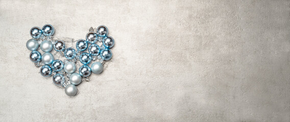 Christmas baubles arranged in a heart shape on a winter background