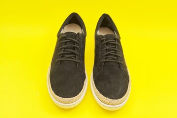 New women's black natural suede sneakers on yellow background, top view