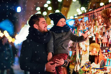 smiling father and son having fun at the christmas market during winter holidays - 390925584