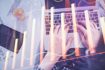 Double exposure of man's hands typing over laptop keyboard and forex chart hologram drawing. Top view. Financial markets concept.