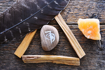 A top view image of a reiki healing symbol and palo santo smudge sticks on a dark wooden table top. 