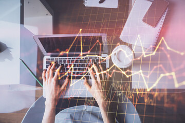 Double exposure of woman hands working on computer and forex chart hologram drawing. Top View. Financial analysis concept.