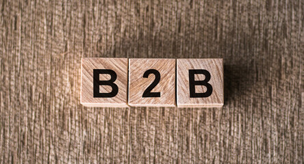 The word B2B business to business on wooden blocks on a brown background top view.