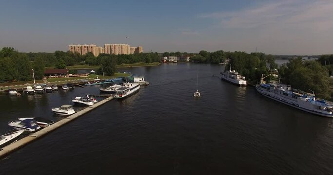 4K high quality calm windless bright summer morning aerial video of Moscow Channel yacht club embankment, green trees, wooden pier and shore with moored anchored boats and yachts near Moscow, Russia