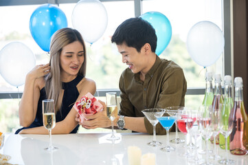 Surprised young couple lover for birthday and Valentine. Hold red present box with gift ribbon bow and balloon.