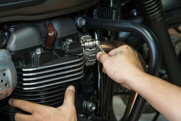 Mechanic using a wrench and socket on exhaust pipe of a motorcycle .maintenance,repair motorcycle concept in garage .selective focus