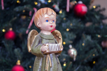 Angel statue with accordion  instrument in front of the christmas tree 