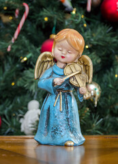 Adorable Angel statue playing  a violin by the Christmas tree 