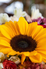 close-up of a beautiful sunflower that is among more flowers of different sizes, detail of the petals and leaf, bouquet of flowers