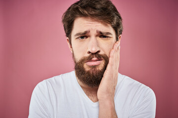 Obraz premium Emotional bearded man in white T-shirt discontent pink background